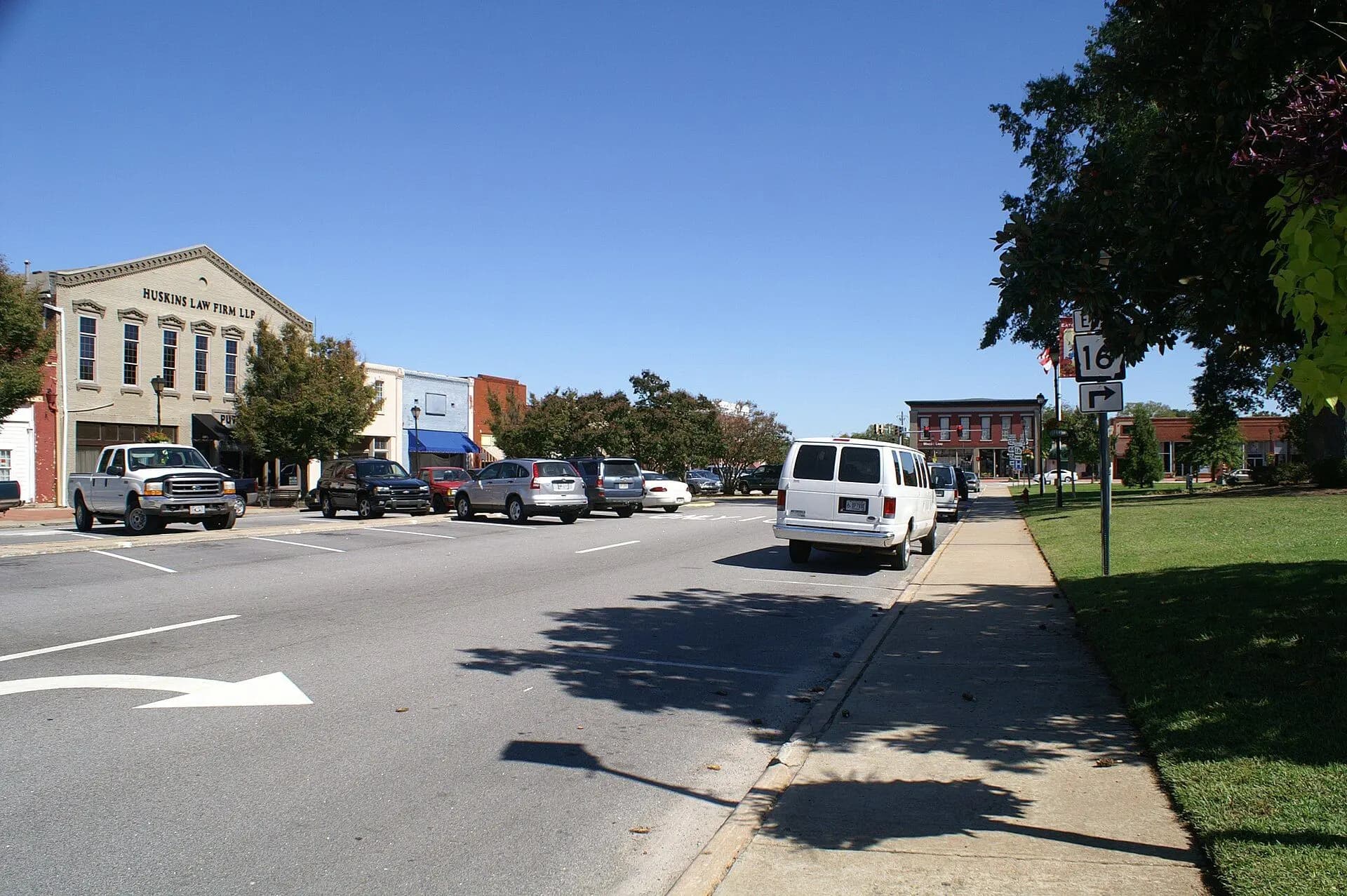 Two-story brick storefronts and parked trucks along West Marion Street in downtown Eatonton, Georgia.