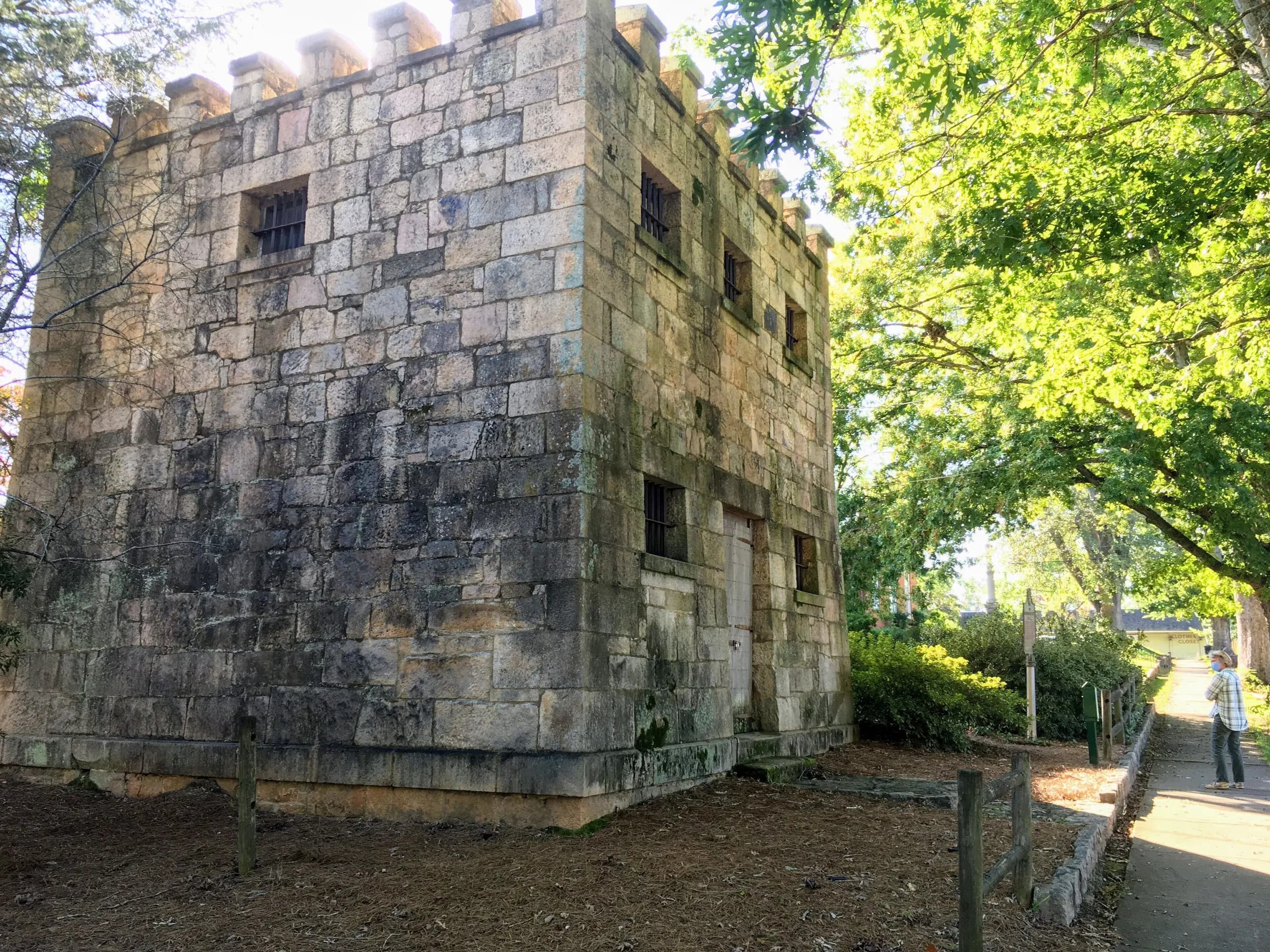 The granite-block Old Greene County Gaol in Greensboro, Georgia, under shade trees.