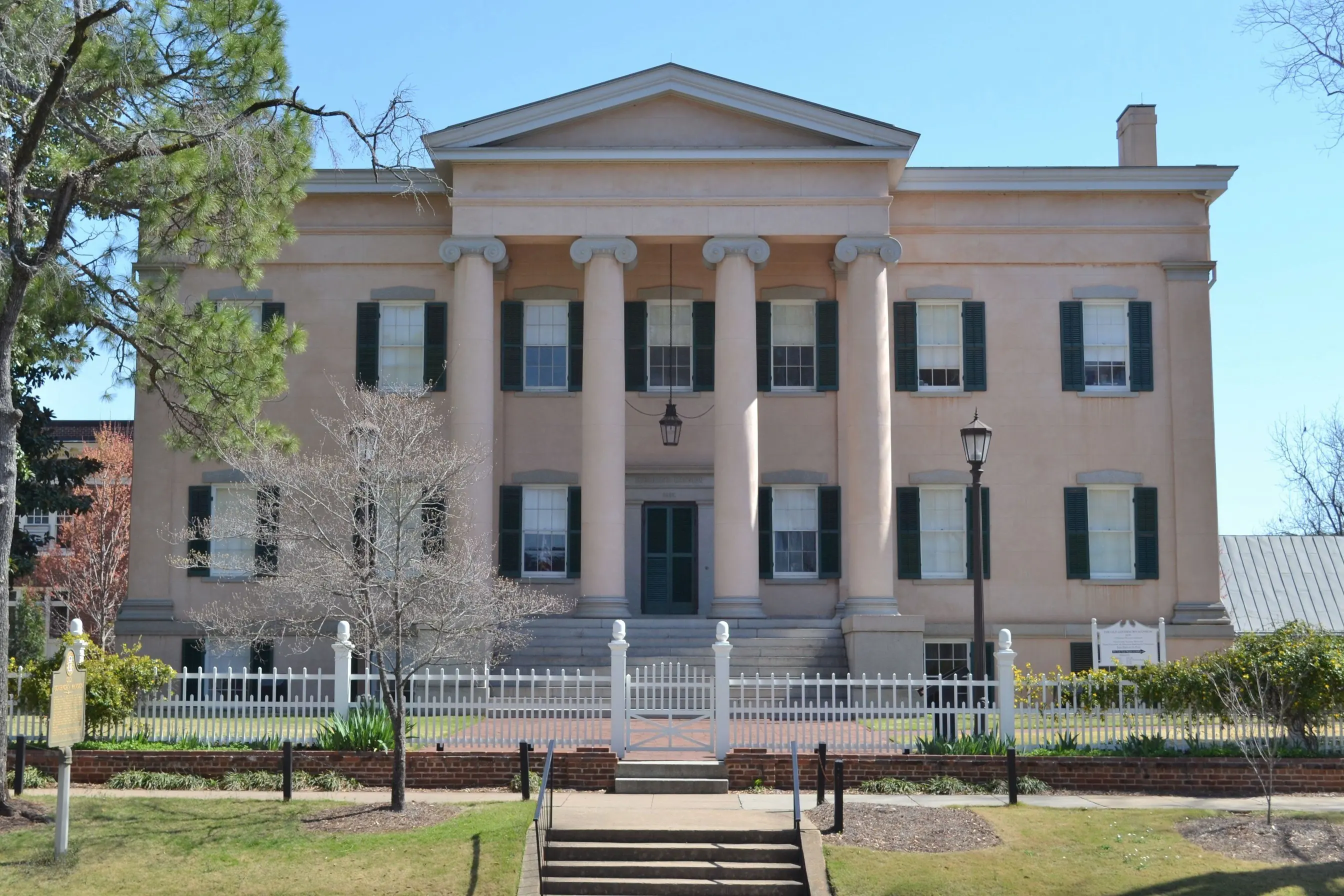 The Greek Revival Old Governor's Mansion in Milledgeville, Georgia, with its columned portico and white picket fence.